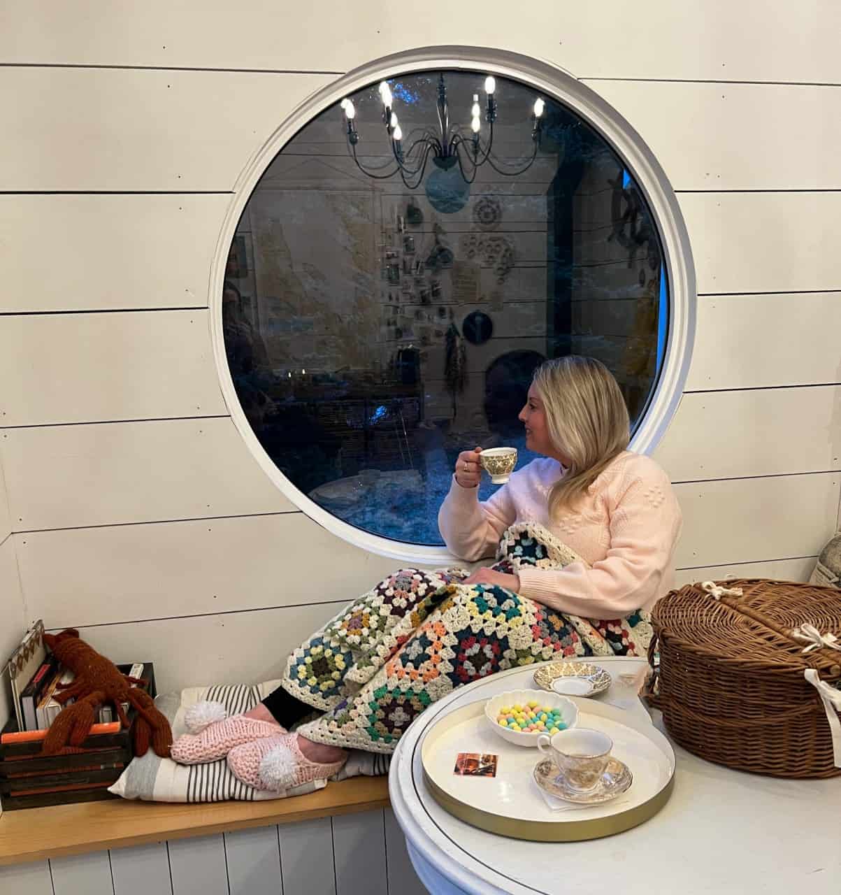 Sipping local blueberry tea at A Little Cup of Sea Newfoundland Canada  - Icebergs can be viewed floating through Conception Harbour Newfoundland through the large porthole window at A Little Cup of Sea beach hut.